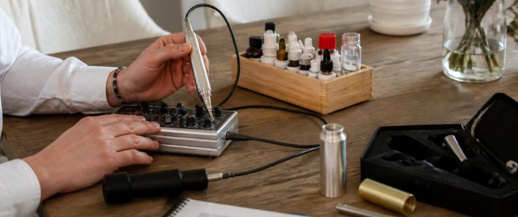 formazione-in-terapia-a-frequenza-con-certificato-il-percorso-2026-1790119812-1 - Herbert Eder - Ricercatore nel campo delle frequenze Una manicure che utilizza un trapano elettrico per unghie su un tavolo di legno, con flaconi di smalto e strumenti per la manicure nelle vicinanze