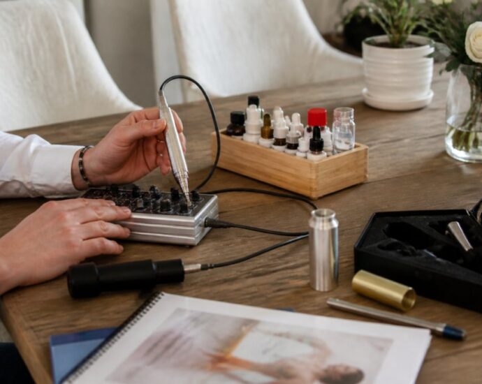 Una manicure che utilizza un trapano elettrico per unghie su un tavolo di legno, con flaconi di smalto e strumenti per la manicure nelle vicinanze