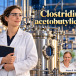 Clostridium acetobutylicum – Anna und Herbert - Herbert Eder - Frequenzforscher Frau mit Schutzbrille und Mappe neben einem metallischen Fermenter unter dem Titel Clostridium acetobutylicum.
